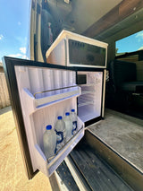 RV rental interior: open fridge with water bottles, a control panel, and seating in a well-equipped camper van.