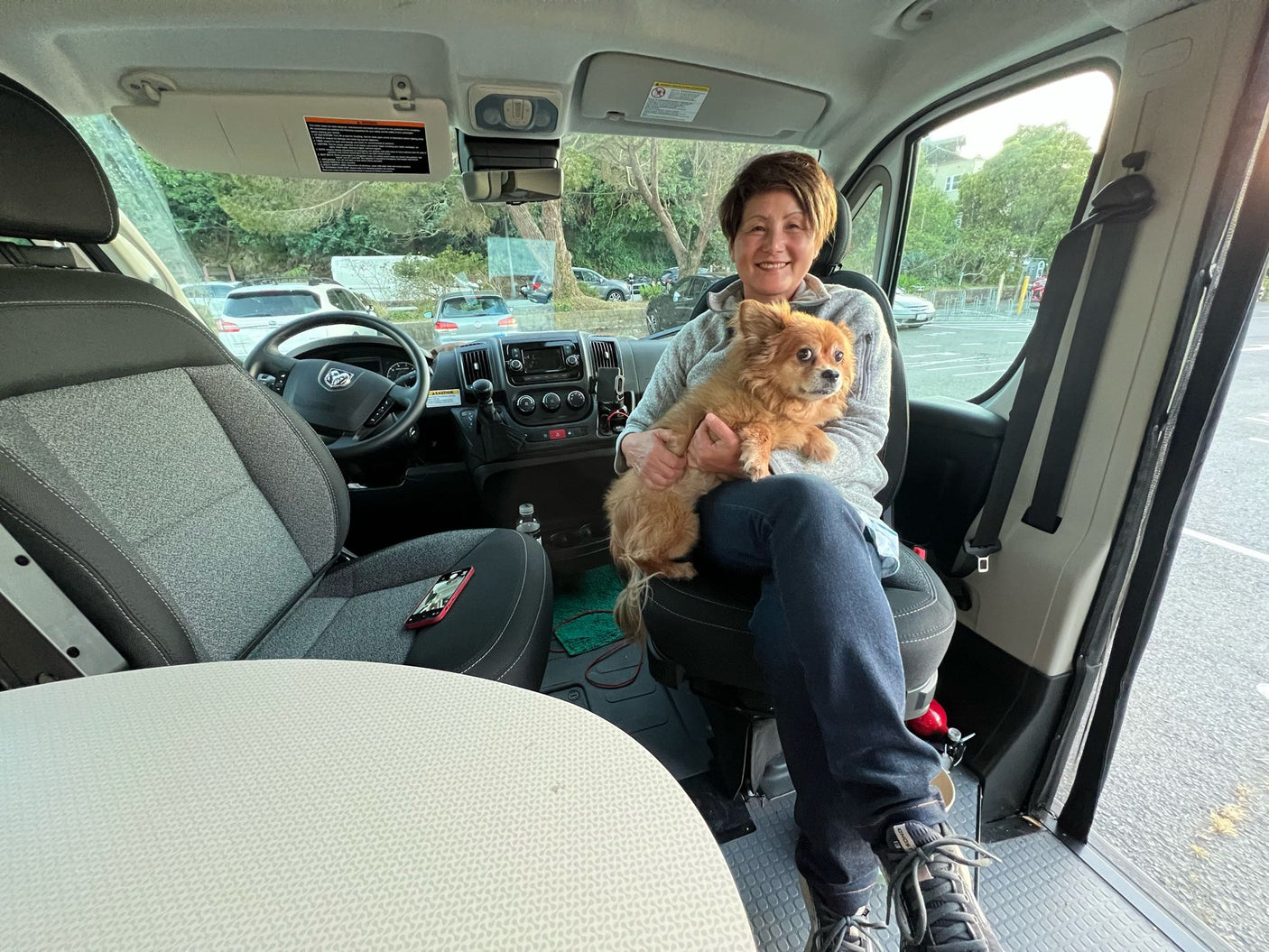 Happy woman and her fluffy dog smile inside a modern RV rental. A comfortable setup for pet-friendly road trip adventures.