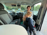 Happy woman and her fluffy dog smile inside a modern RV rental. A comfortable setup for pet-friendly road trip adventures.