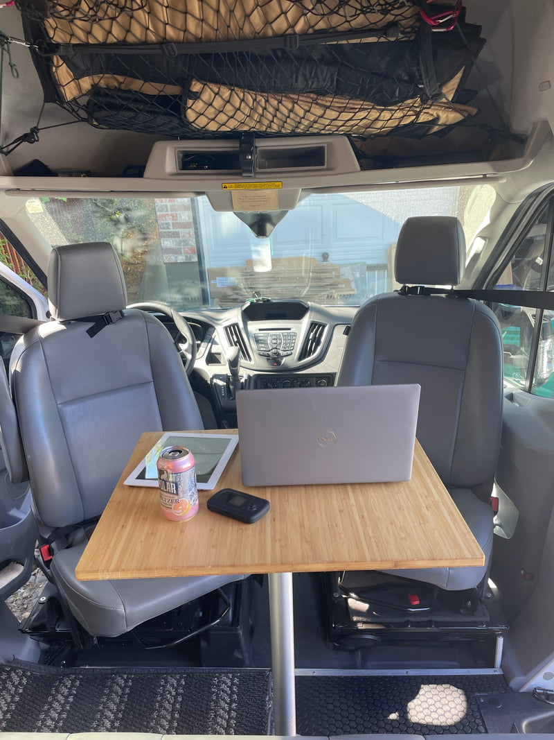 RV rental: Van interior featuring a mobile office setup with laptop, tablet, and table between swiveling seats. — photo 9