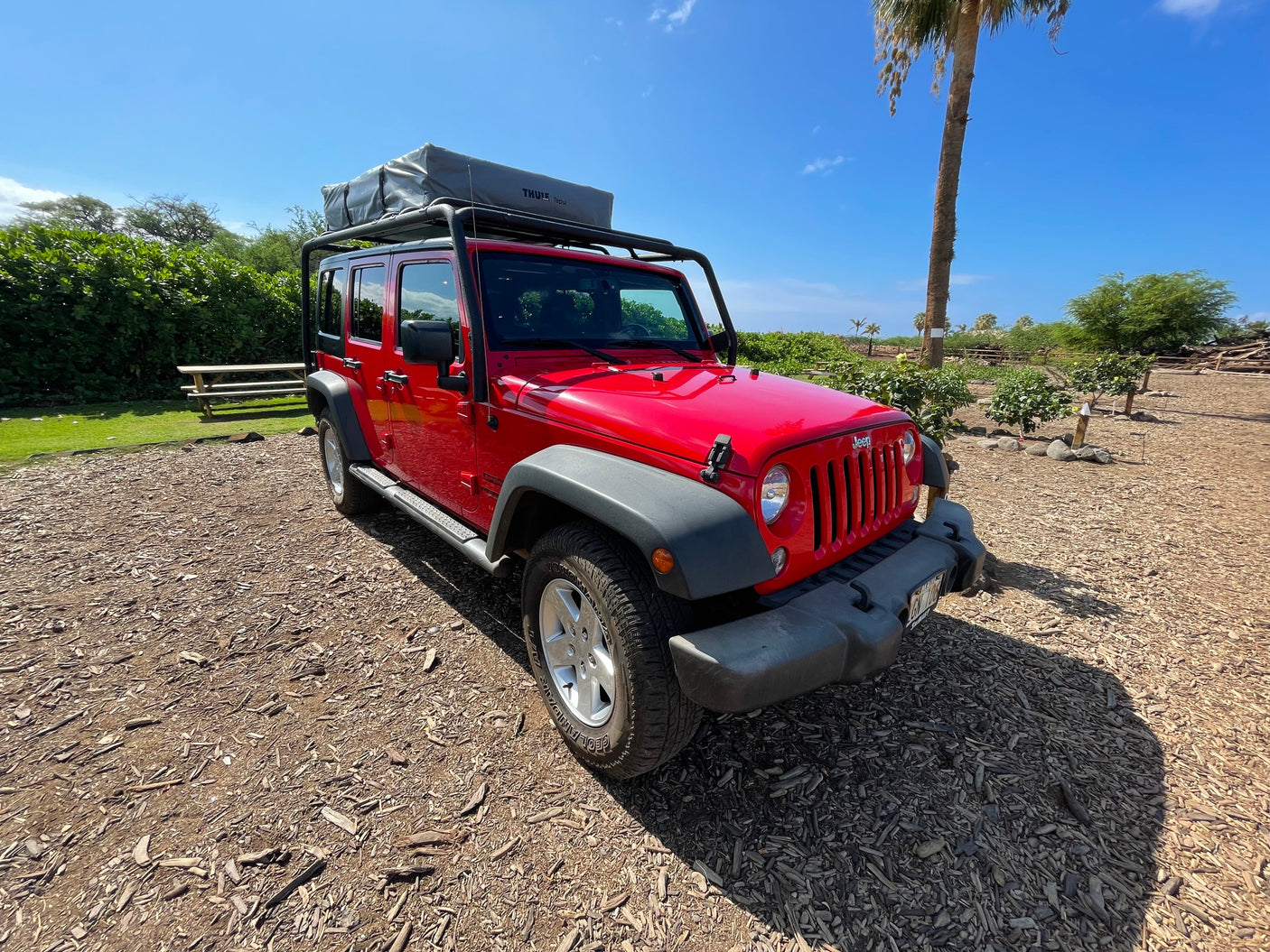 A vibrant red Jeep Wrangler, featuring a rooftop tent, perfect for your next RV rental adventure.
