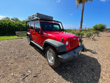 A vibrant red Jeep Wrangler, featuring a rooftop tent, perfect for your next RV rental adventure.