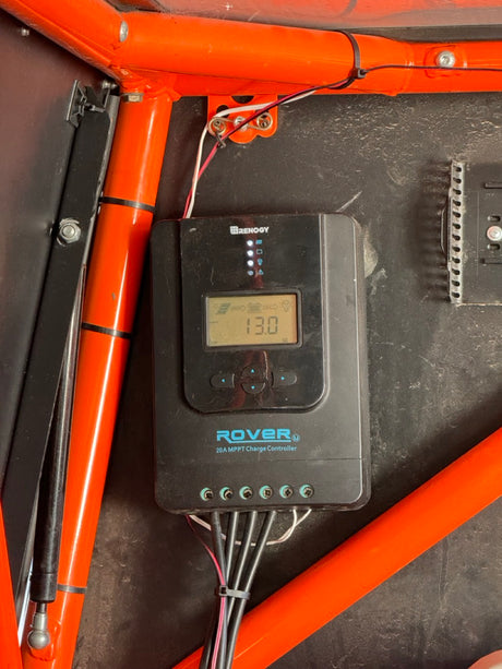 An RV rental's Renogy Rover solar charge controller, displaying 13.0V, vital for off-grid battery power.