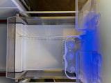 Inside an RV rental fridge: clear shelves, water bottles, and a blue interior light for your travel convenience.