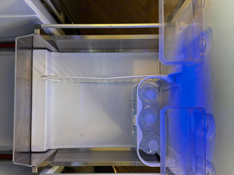 Inside an RV rental fridge: clear shelves, water bottles, and a blue interior light for your travel convenience.