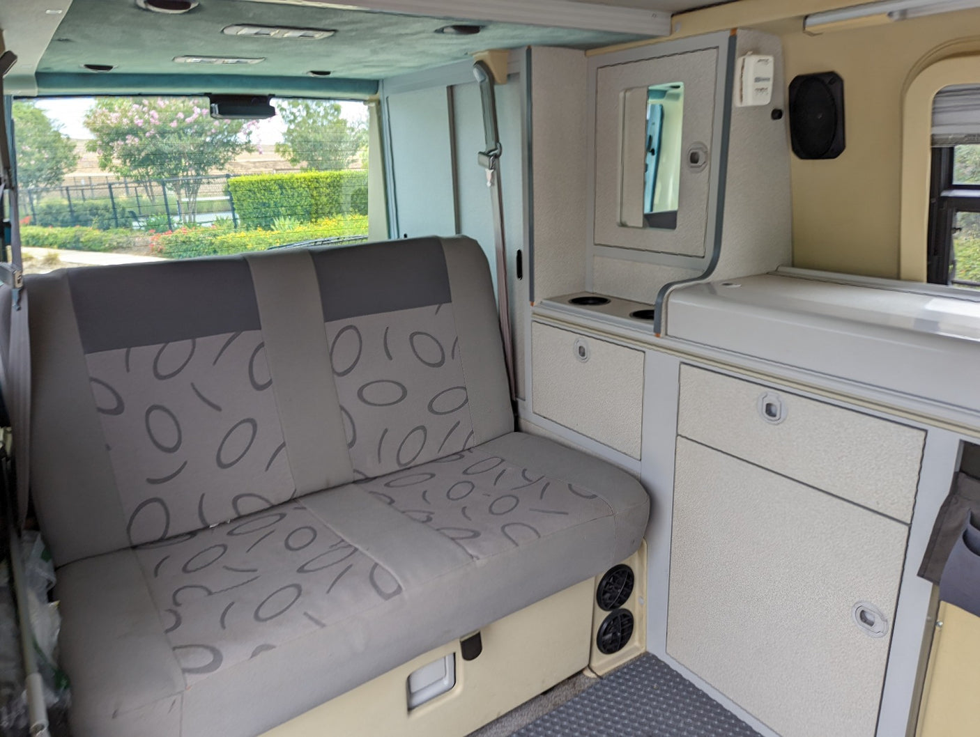 RV rental interior featuring a patterned bench seat, compact kitchenette, and storage. Ready for your next adventure!