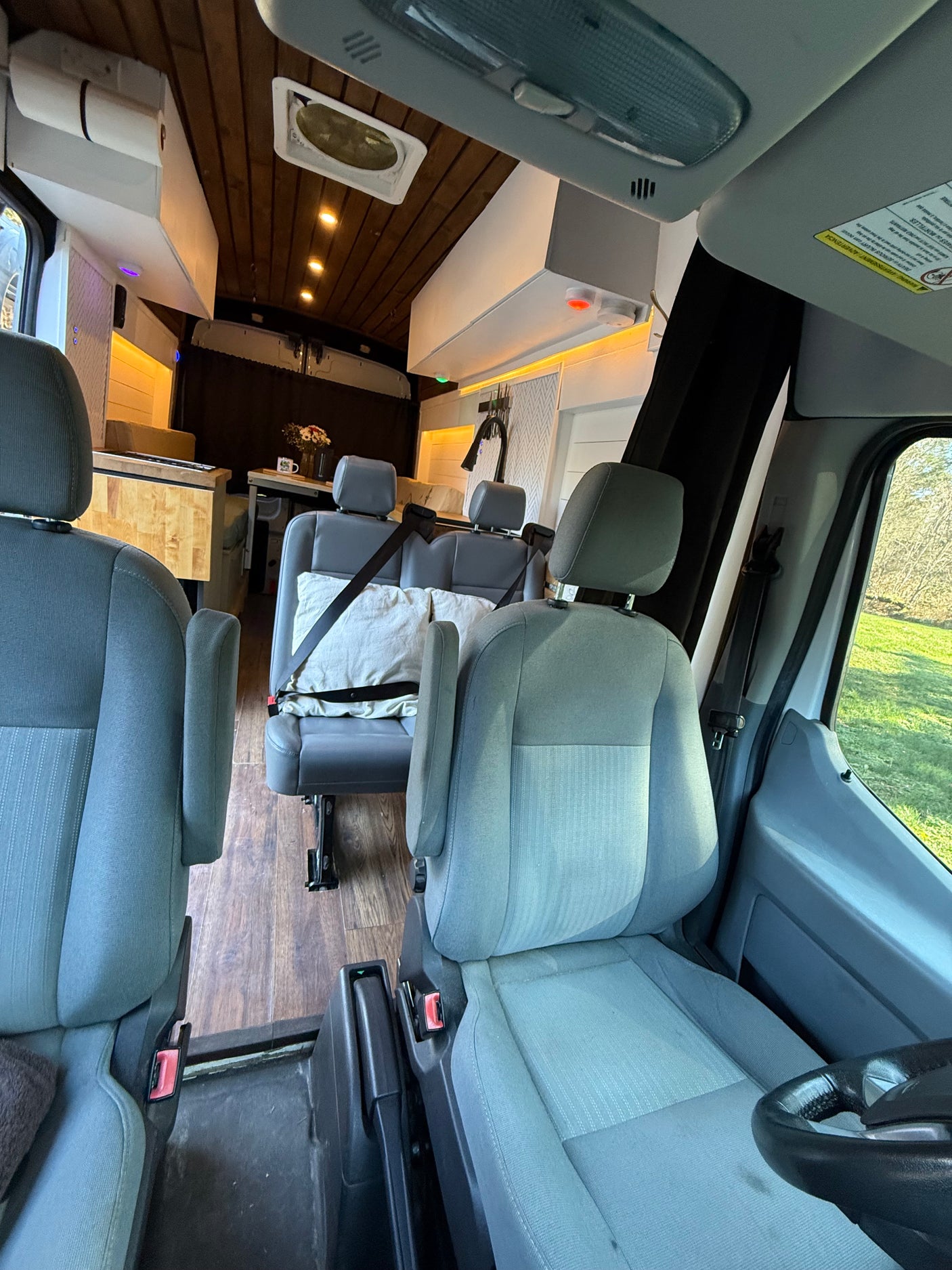 RV rental interior: View from front seats into a cozy camper van living area featuring a kitchen, wooden ceiling, and additional seating.