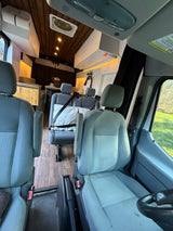 RV rental interior: View from front seats into a cozy camper van living area featuring a kitchen, wooden ceiling, and additional seating.