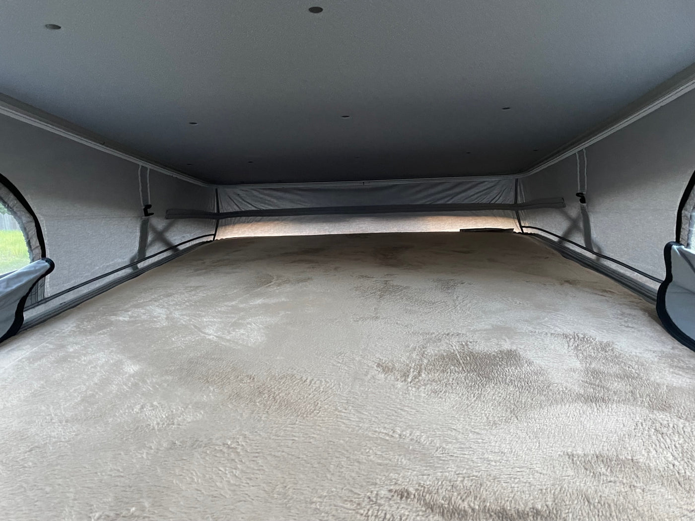 An RV rental's cozy pop-top sleeping area. A plush, light-colored bed fills the frame, surrounded by fabric tent walls. — photo 8