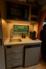 Compact RV rental kitchenette: microwave, sink, fridge, and coffee maker, ready for adventure.