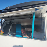 An RV rental's open back hatch reveals a converted camper interior with a vibrant bed, blue accents, and decor.