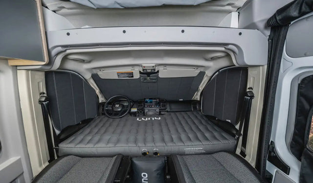  and textured gray flooring.|Cozy rv rental interior: A quilted bed with pillows inside a rooftop tent