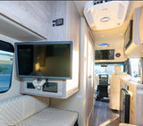 Explore this RV rental's cozy interior, featuring a flat-screen TV, comfortable seating, and a kitchenette, leading to the cockpit.