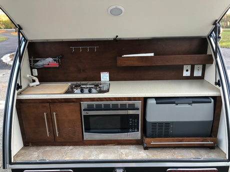 Teardrop RV rental's rear galley: Complete outdoor kitchen with sink, stove, microwave, fridge, and storage.