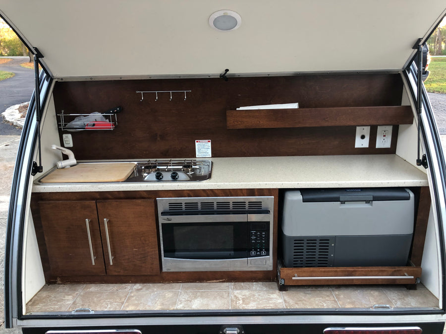 Teardrop RV rental's rear galley: Complete outdoor kitchen with sink, stove, microwave, fridge, and storage.