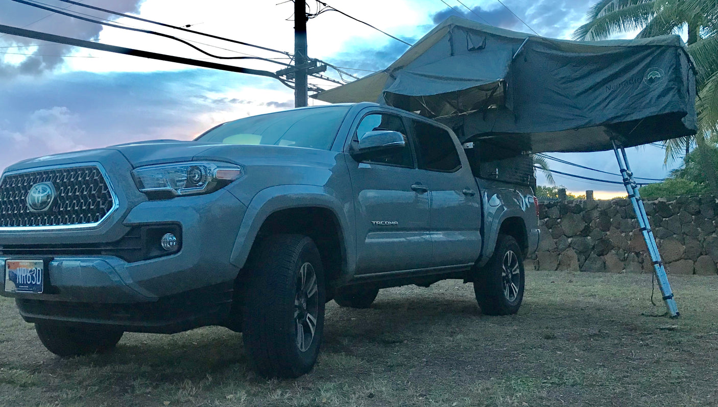 Gray Toyota Tacoma pickup truck with a deployed roof-top tent, a versatile RV rental option for camping and overlanding.