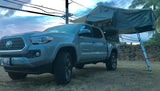 Gray Toyota Tacoma pickup truck with a deployed roof-top tent, a versatile RV rental option for camping and overlanding.