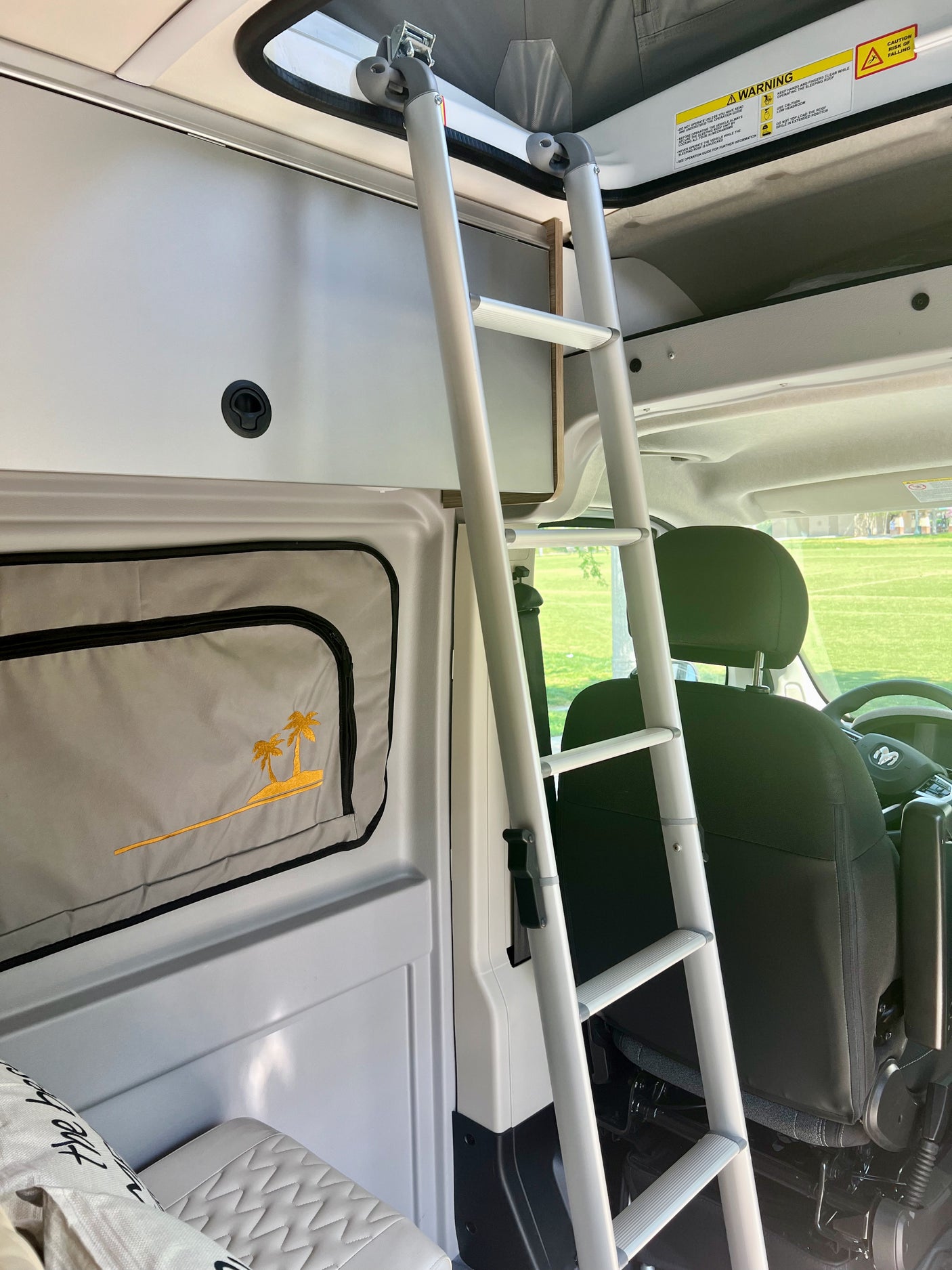 RV rental interior featuring a ladder to an upper sleeping area, ideal for family travel.