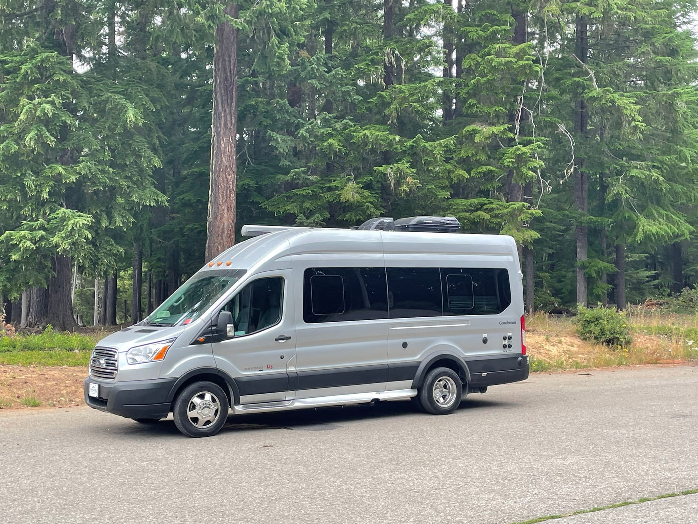  and an outdoor table set up for camping in a lush forest.|Silver campervan RV rental parked at an outdoor campsite — photo 15