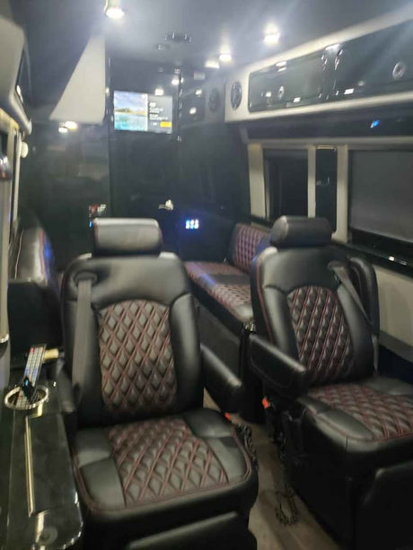 Plush black leather diamond-quilted seats and a TV fill this premium RV rental interior, ready for travel.