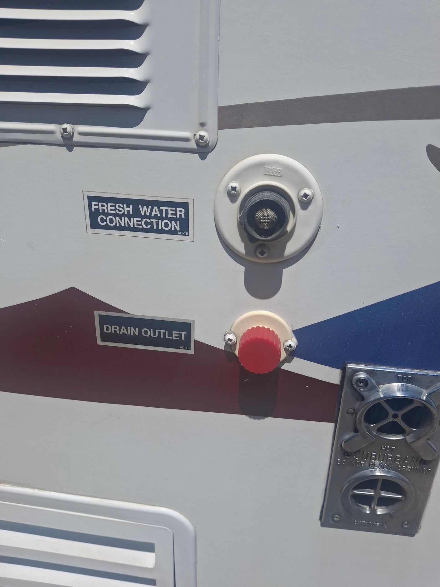 View of an RV rental's side: Fresh water fill, drain outlet, and Suburban water heater vent.