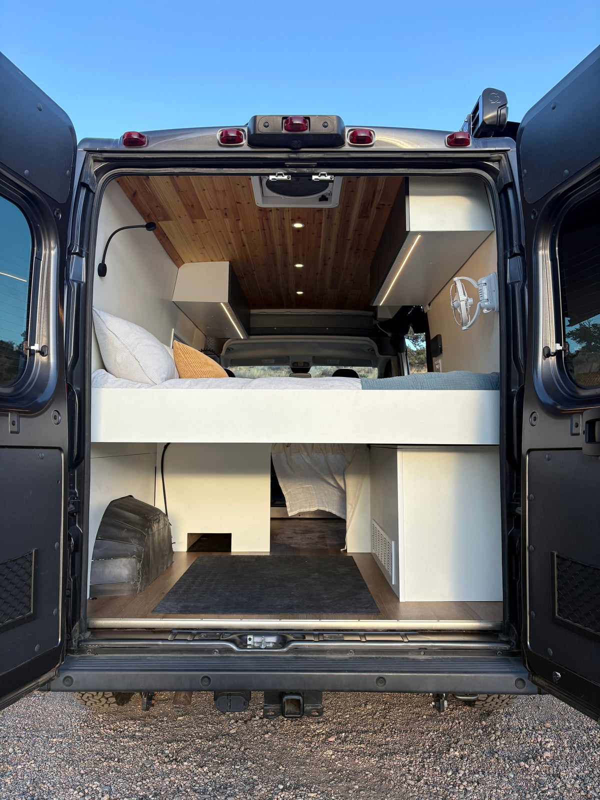 Experience this custom **rv rental** camper van interior. Features a comfy bed, wood ceiling, and ample storage from the rear. — photo 20