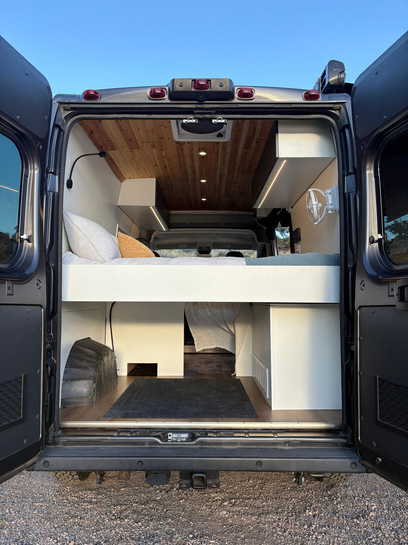 Experience this custom **rv rental** camper van interior. Features a comfy bed, wood ceiling, and ample storage from the rear. — photo 20
