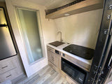 RV rental interior: Kitchenette with sink, stovetop, microwave, and adjacent shower. Compact and functional design for travel.
