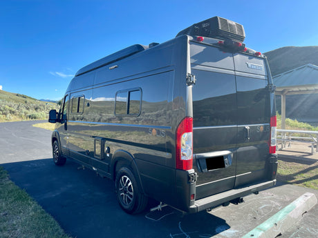 Dark grey Winnebago Solis RV rental van parked on asphalt with mountains in background. Perfect for outdoor adventure.