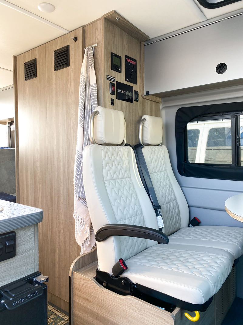 An RV rental's Winnebago interior: cream quilted seats, control panels, storage, and modern design. — photo 7