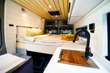 This RV rental boasts a comfy bed, wood-paneled ceiling, and a built-in sink/counter for a perfect compact living space.