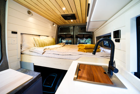 This RV rental boasts a comfy bed, wood-paneled ceiling, and a built-in sink/counter for a perfect compact living space.