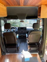 Front cabin of an RV rental, showcasing driver/passenger seats, dashboard, & custom wooden interior.