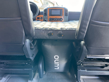 RV rental interior: A Luno air mattress and support create a bed between the front seats, ideal for travel comfort.