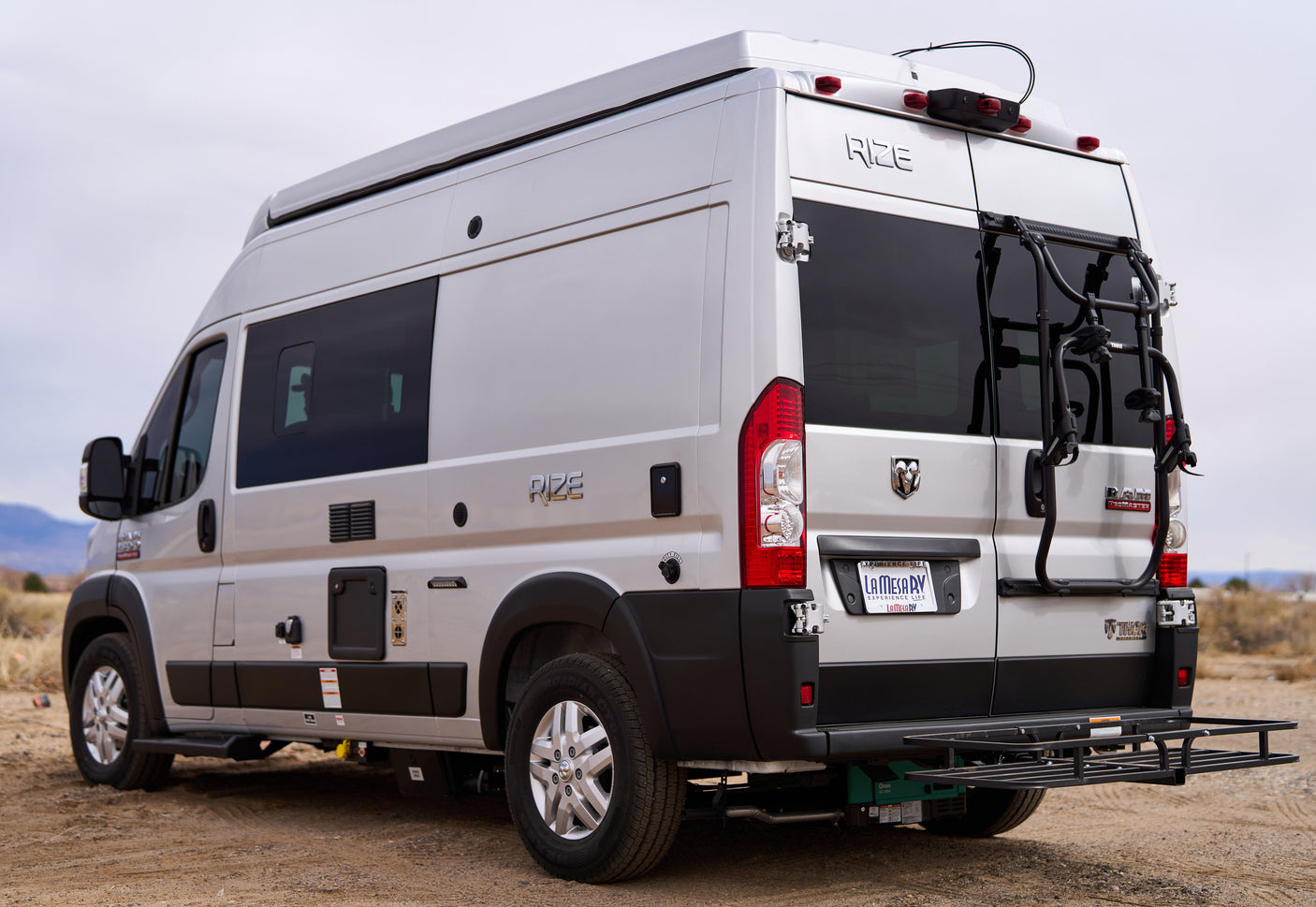 Silver Thor Rize camper van, an RV rental, with a rear-mounted bike rack and cargo carrier.