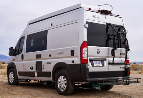 Silver Thor Rize camper van, an RV rental, with a rear-mounted bike rack and cargo carrier.