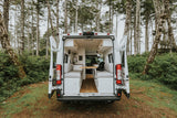 Custom RV rental campervan's cozy interior, open to a peaceful forest setting. Ideal for nature escapes.