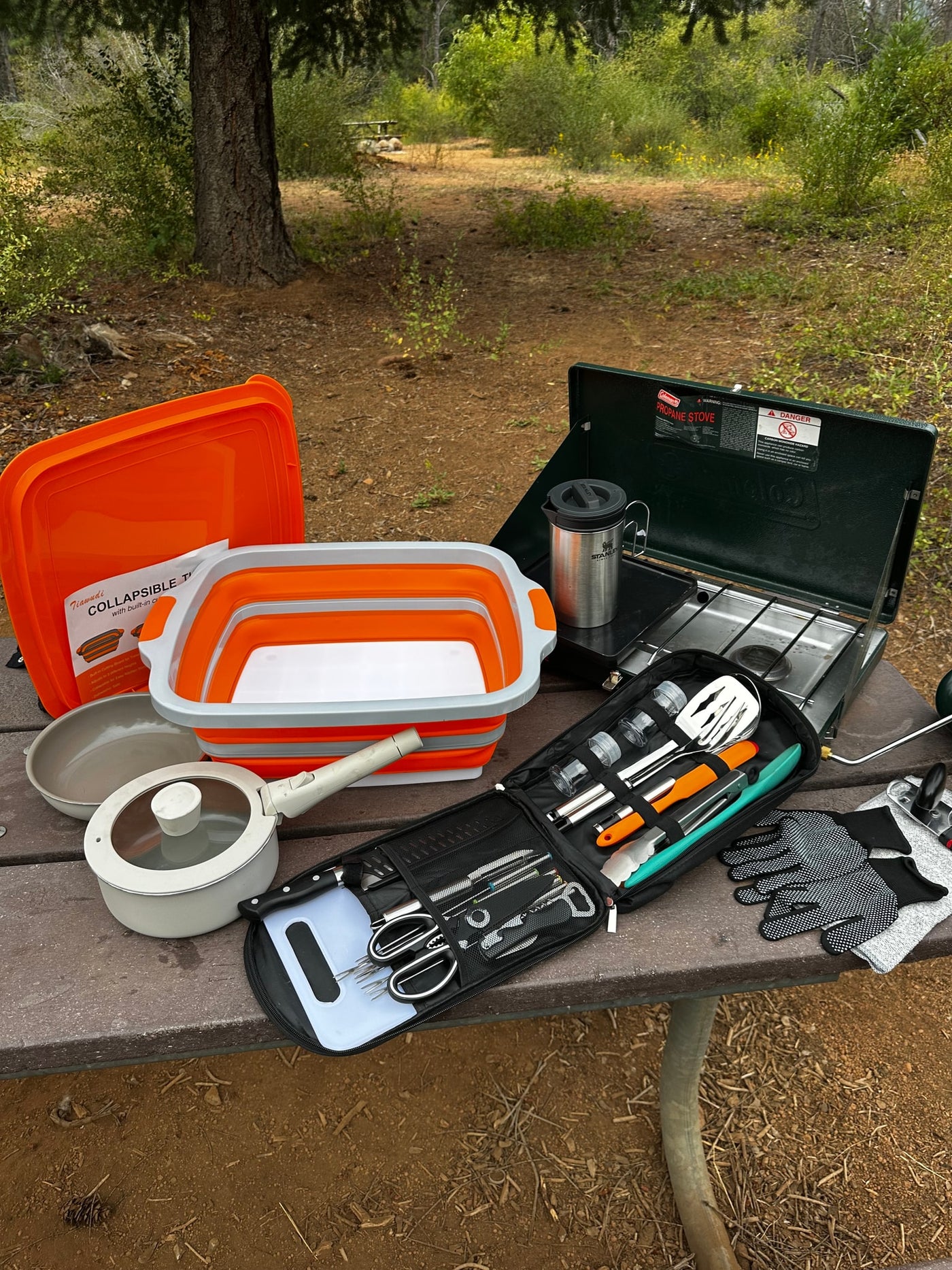 RV rental cooking setup: Coleman stove, collapsible washbasin, pots, and a full kitchen utensil kit, ready for camp meals. — photo 14