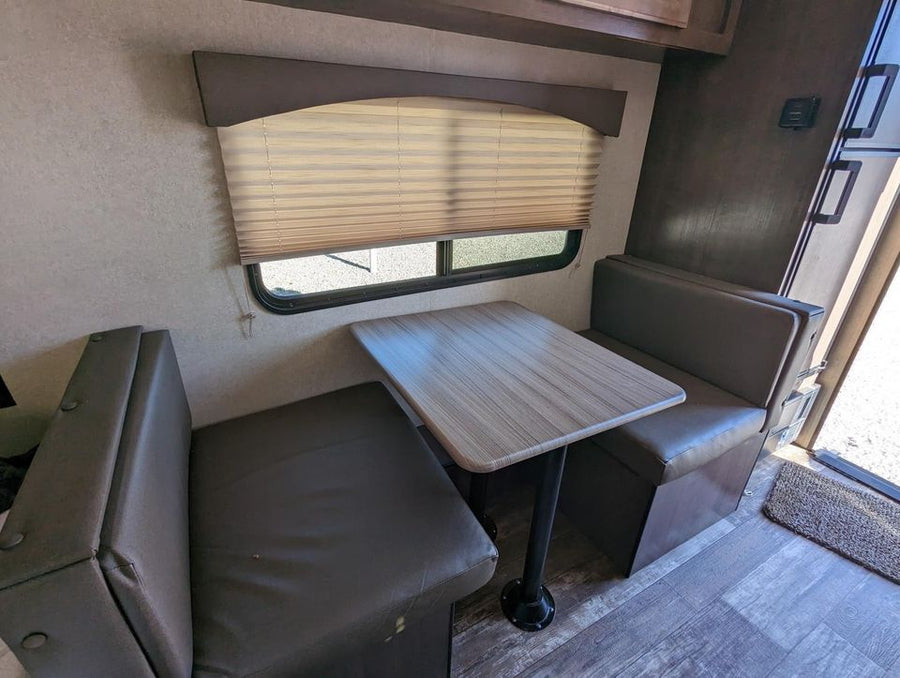  and an adjacent bed.|Compact RV rental interior: features an unused bed in plastic