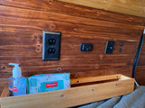 Inside this RV rental, find a rich wood wall with essential power outlets, charging ports, and a handy bedside shelf.