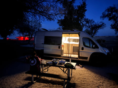 Van life evening: cozy rv rental lights up a picnic dinner under a twilight sky. Perfect for camping adventures.