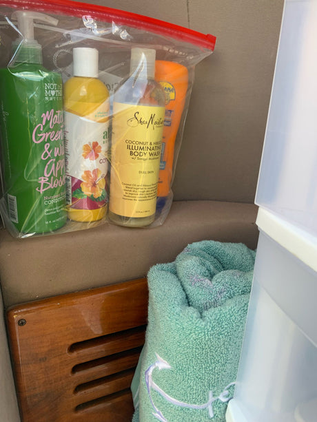 Toiletries organized in a clear bag for an RV rental trip, with a towel & storage containers in a compact space.