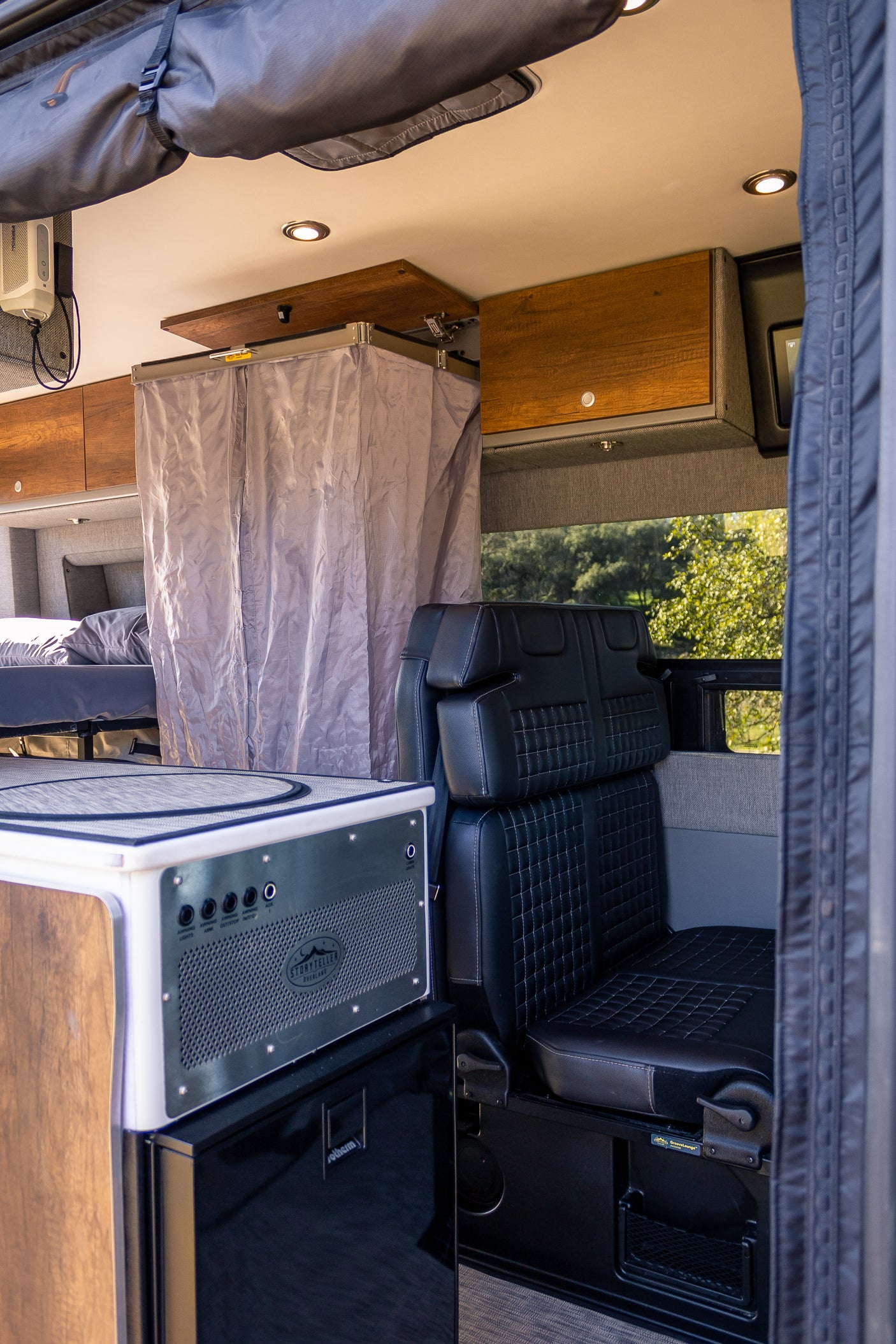 Experience comfort in this RV rental's mobile living space: kitchen, cozy bed, and passenger seating in a custom camper van.