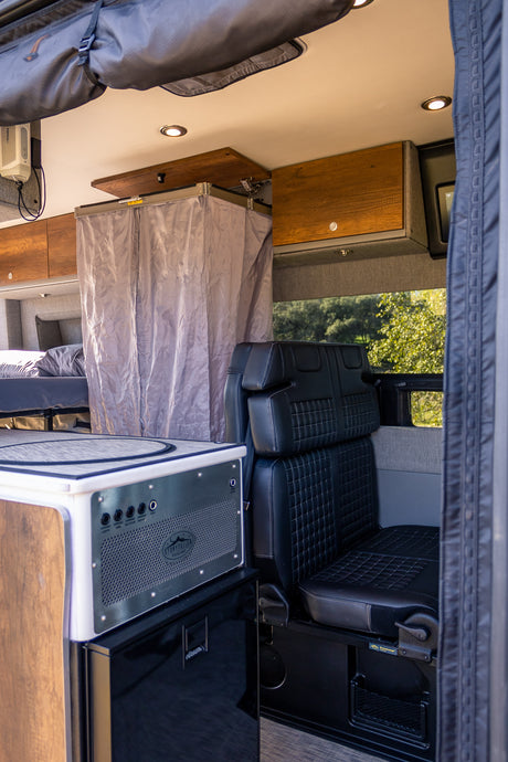 Experience comfort in this RV rental's mobile living space: kitchen, cozy bed, and passenger seating in a custom camper van.