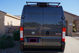Dark grey Ram ProMaster van's rear, ideal for RV rental. Features logo, roof rack, and reflective doors.