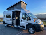 Silver pop-top camper van, perfect for an rv rental adventure, with its side door open revealing a cozy interior.