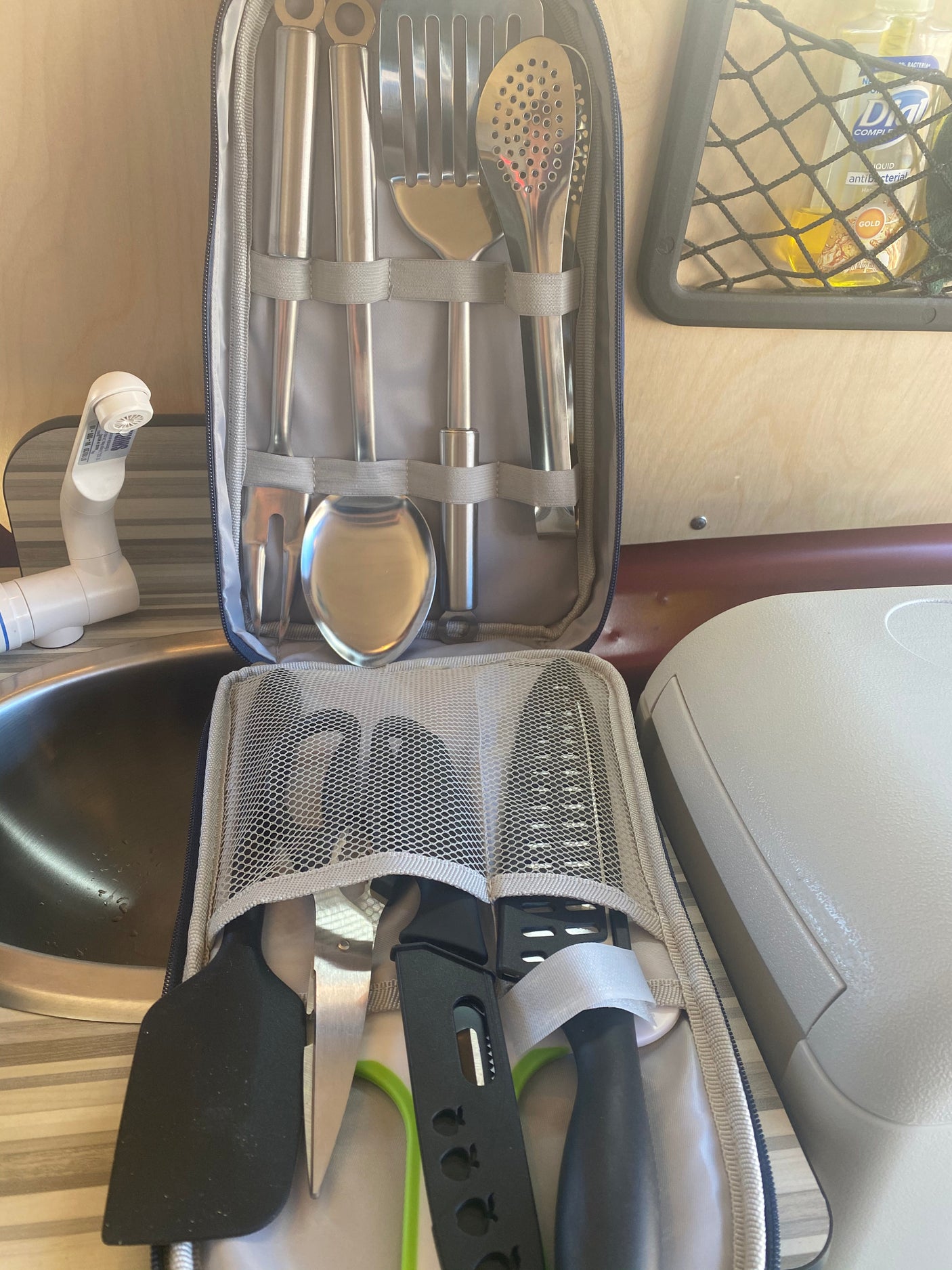 RV rental ready: compact kitchen featuring neatly packed cooking utensils, a knife, spatula, and sink for travelers.