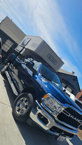 Angled view: dark blue Ram truck with a grey 'SCOUT' truck camper. Ideal for your next RV rental adventure.