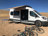 **RV rental** fun: A converted van with an awning, family, and bikes for outdoor adventures in the desert. Perfect for van life camping.