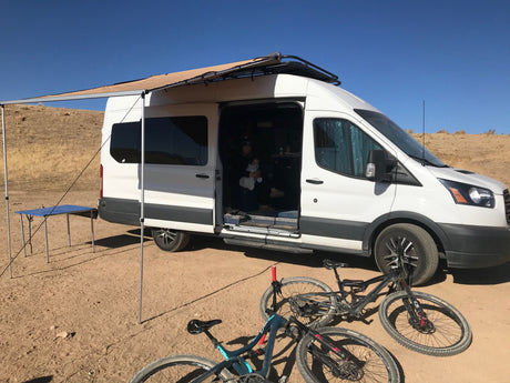 **RV rental** fun: A converted van with an awning, family, and bikes for outdoor adventures in the desert. Perfect for van life camping.